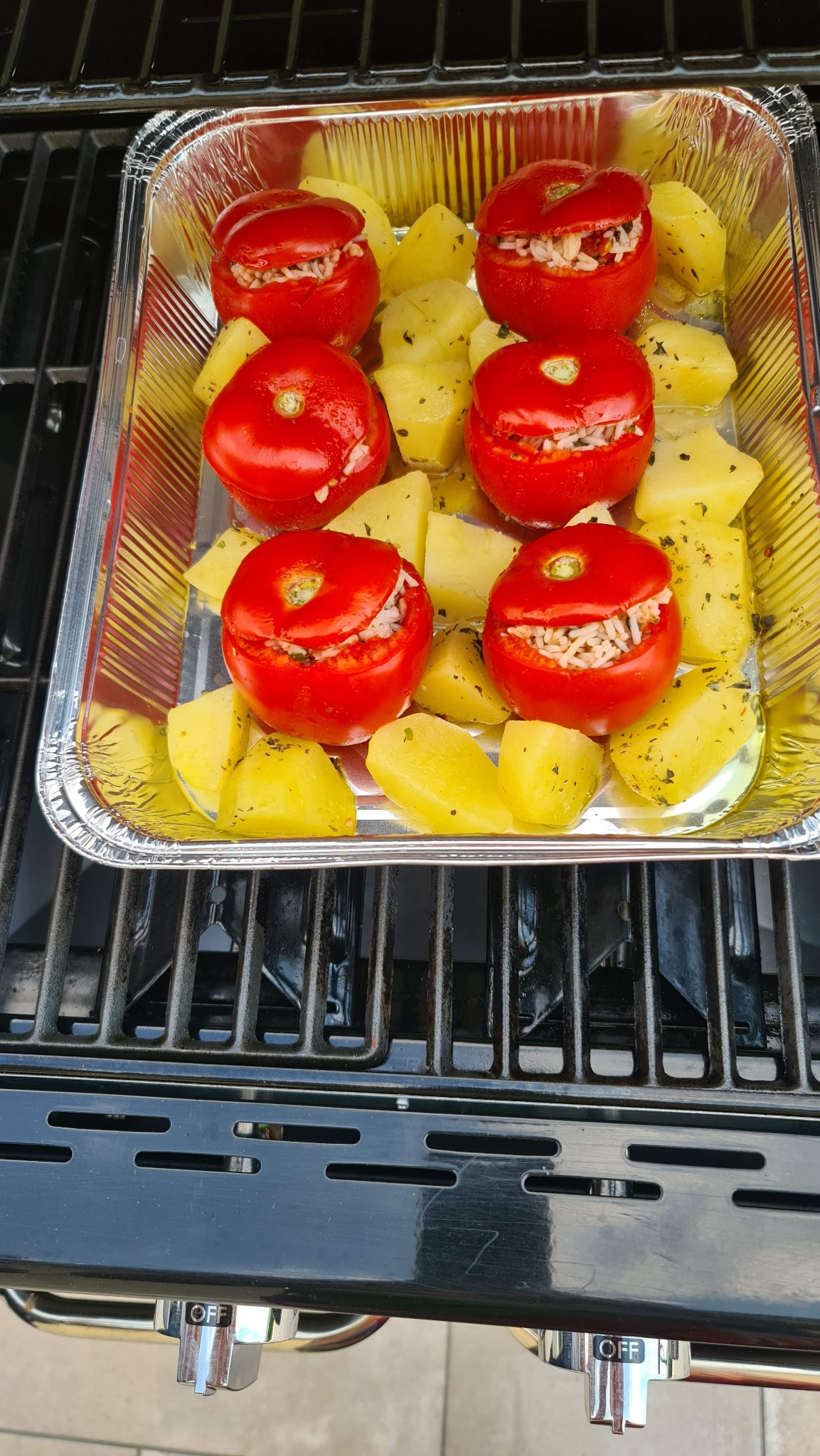 Sei pomodori ripieni ancora rossi con le patate nella vaschetta sul barbecue